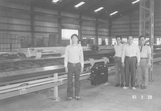 1985年擴廠引進牽引機，與日本技師合影